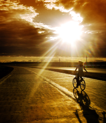 kobieta na rowerze przy zachodzącym słońcu